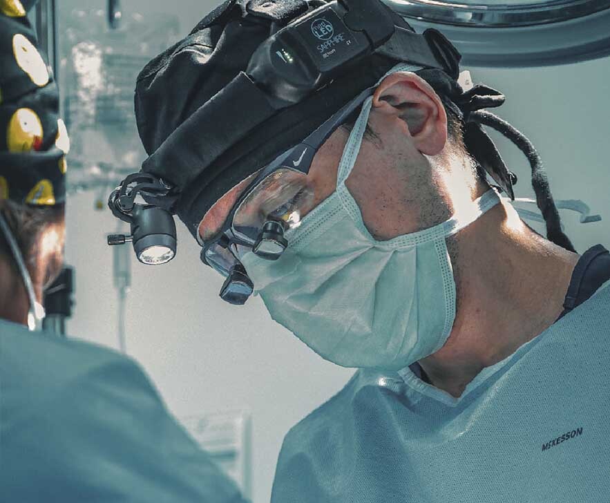 Plastic surgeon performing penile enhancement surgery with a surgical team in a New York operating room